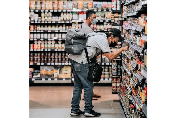 Image A man bending down to read a food label on the shelf in a grocery store.